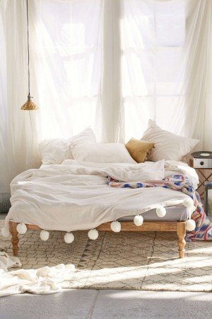A bed styled with pom poms, perfect for creating the ultimate bohemian bedroom.