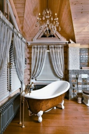 An elegant log cabin bathroom with a clawfoot bathtub and chandelier.