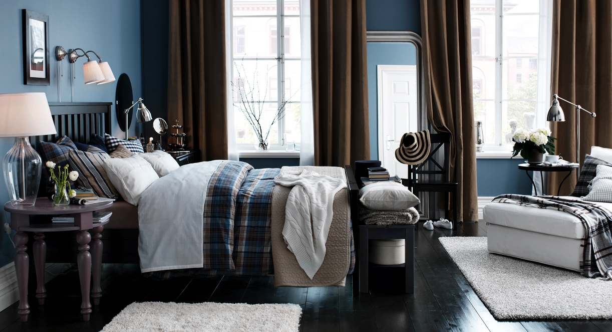 A bedroom with blue walls and black furniture.