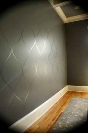 A room with a gray wall and a wooden floor showcasing attention-grabbing examples of feature wallpaper.