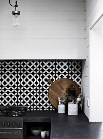 An optical art-inspired black and white tiled backsplash in a kitchen.