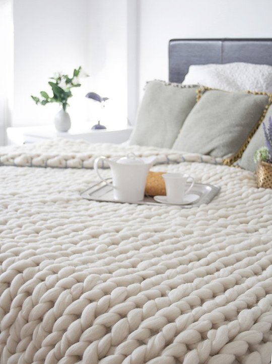 A bed with a soft knit blanket on it.