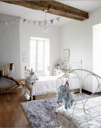 A girl's bedroom with two beds and a rocking horse in a gorgeous home.