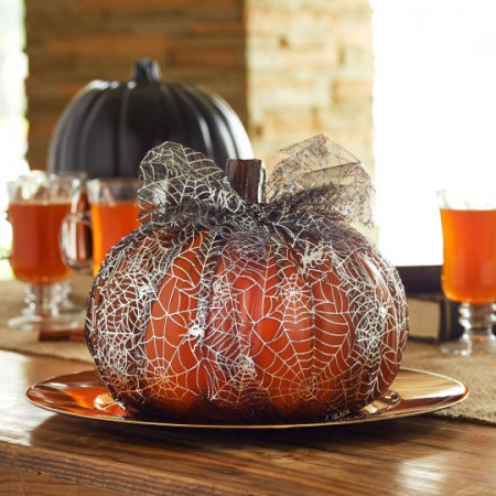 A spider web-decorated pumpkin on a table at Michaels.