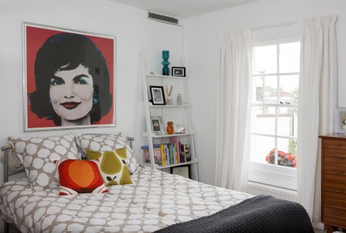 A bedroom with a pop art painting on the wall.