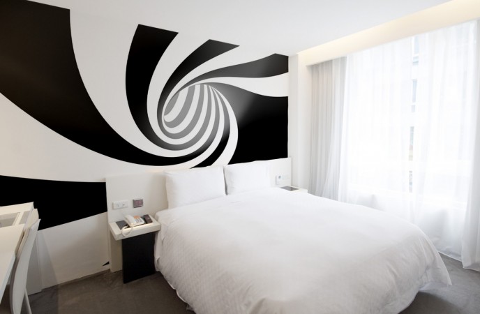 A black and white bedroom with an optical art spiral wall mural.
