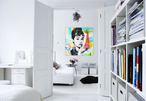 A white bedroom with a pop art painting on the wall.