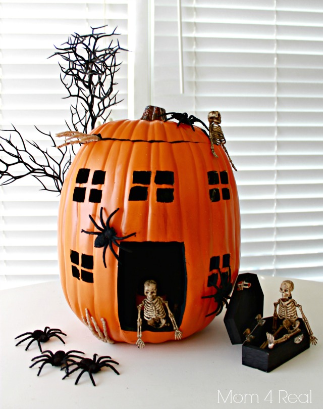 Michaels Custom Carved Pumpkins creates a spooky pumpkin house for Halloween, adorned with spiders and skeletons.