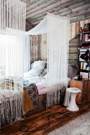 A bedroom with a canopy bed and bookshelves styled for the ultimate bohemian vibe.
