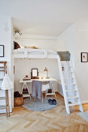 A small bedroom with a loft bed and desk featuring a mesmerising mezzanine balcony.