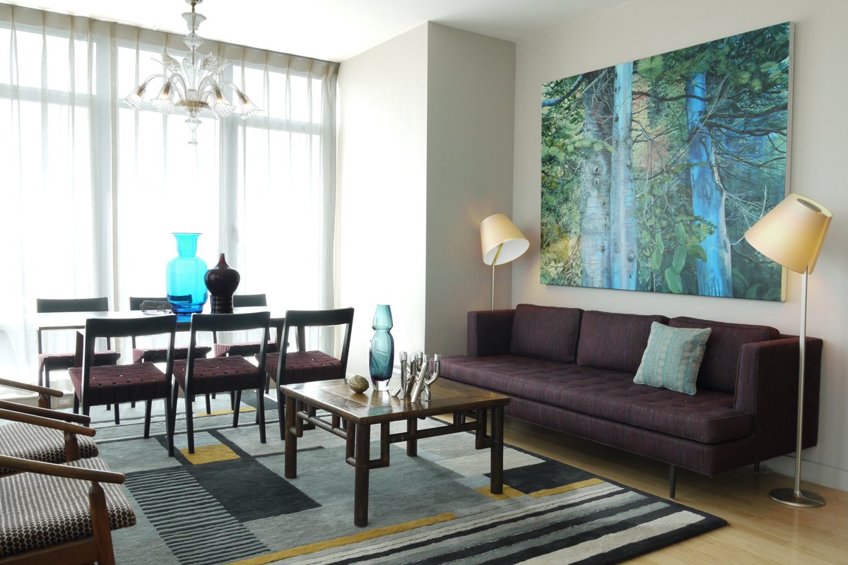 An elegant living room with a large painting on the wall featuring a brown interior color scheme.