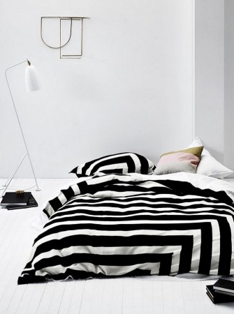 A black and white striped duvet cover in a bedroom with optical art.