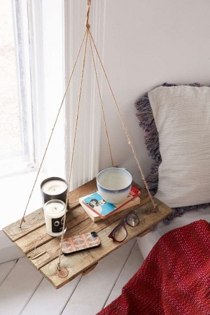 A wooden tray hanging from a wall in a bedroom with nightstands.