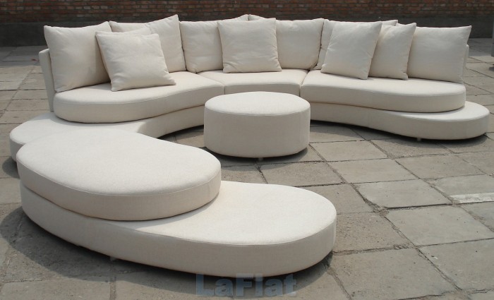A unique white sectional sofa with white cushions and a coffee table.