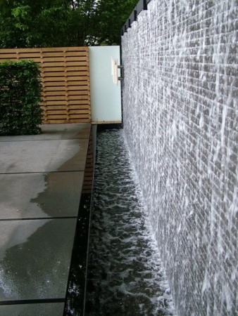 A water feature with water walls in a garden.