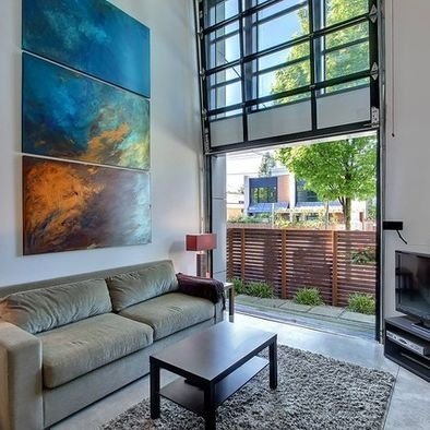 A vertical living room with a large painting on the wall.