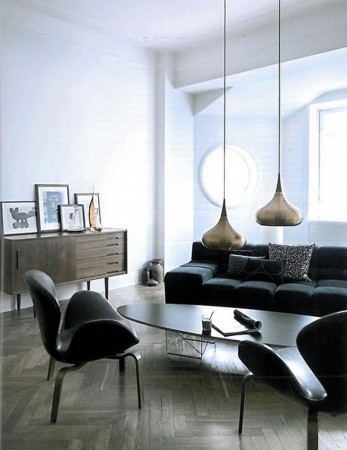A Mid-Century Modern style living room with black furniture and wooden floors.