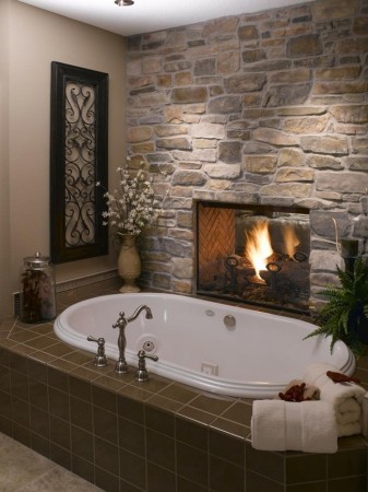 A bathroom featuring a stone fireplace and jacuzzi tub.