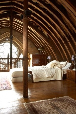 An attic bedroom with wooden beams and a bed in a church-turned-home.