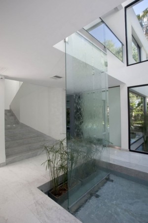 A contemporary house with glass walls incorporating a water feature.