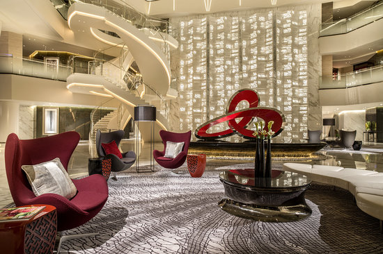 The lobby of a hotel with red chairs and a spiral staircase.