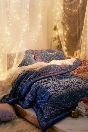 A bed with hanging lights for the ultimate bohemian bedroom styling.
