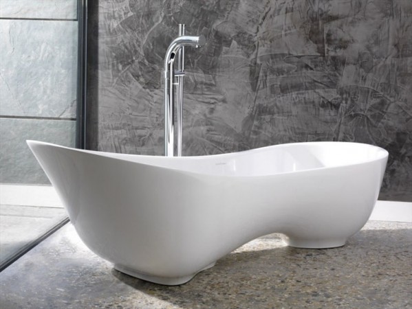 A white bathtub in front of a concrete wall.