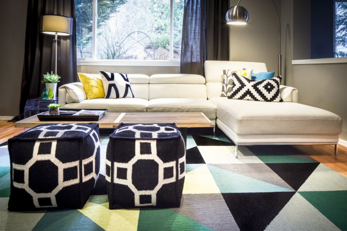 A living room with a white couch and a colorful rug, getting graphic with your interiors.