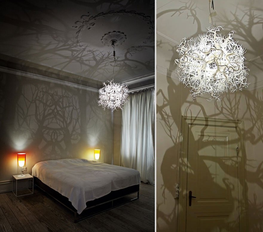 A room with a bed and a lamp featuring a chandelier above.