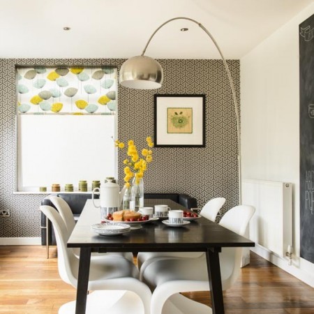 A dining room with white chairs and a retro chalkboard wall.