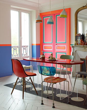 A dining room with a colorful table and chairs featuring bold neon hues.