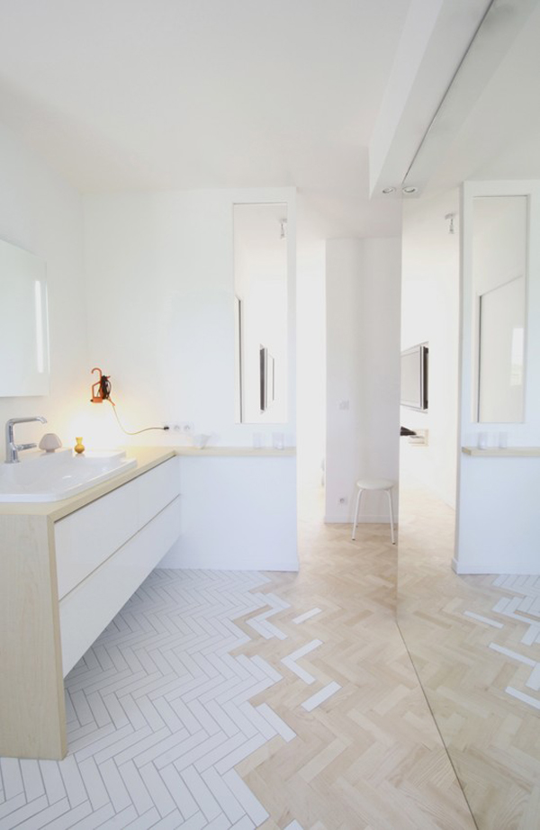 A white bathroom with a herringbone floor.