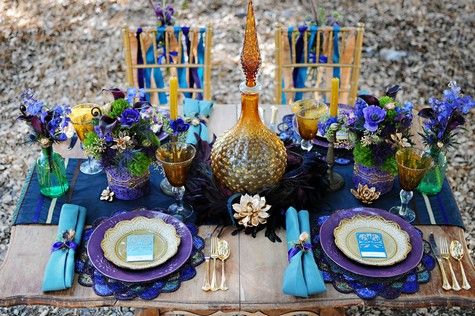 A table set with purple, blue, and gold decorations inspired by peacock beauty for your home.
