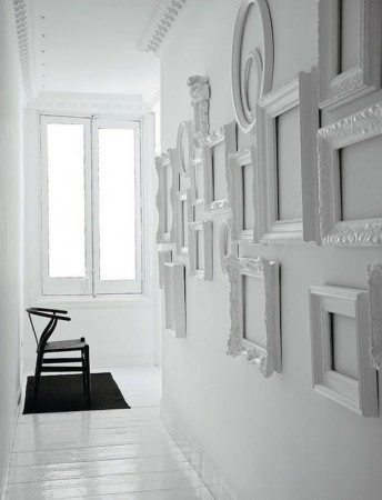 A white hallway with framed pictures and a chair. Keywords: hallway, framed pictures
