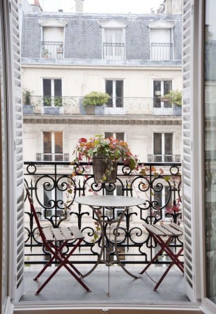 A charming balcony in Paris showcasing a table and chairs.