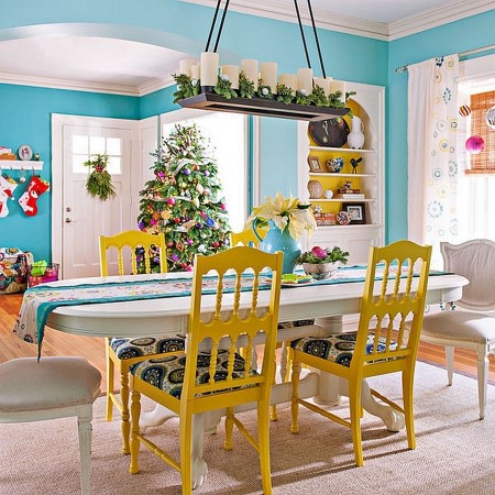 A dining room with blue walls and yellow chairs featuring alternative Christmas colors.