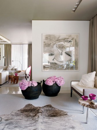 A living room with vases of flowers and a cowhide rug featuring haute couture interior design.