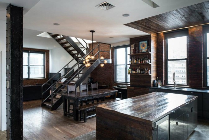 A kitchen with a wooden table and a staircase in an industrial style for the modern man.