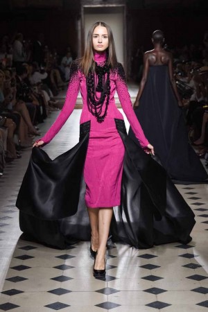 A model showcases a pink dress on the runway.