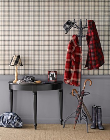 A plaid coat rack with cozy coats and umbrellas on it.