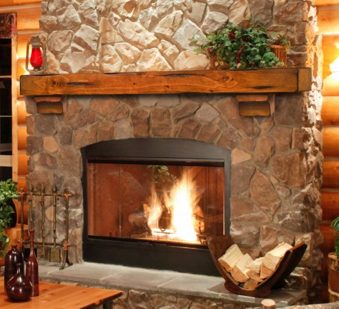 Simple wood mantel enhances stone fireplace