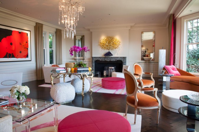 A living room with haute couture orange furniture and a fireplace.