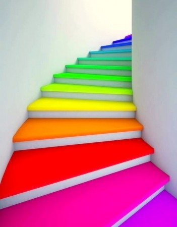 A rainbow colored staircase leading up to a white wall, showcasing bold neon hues.