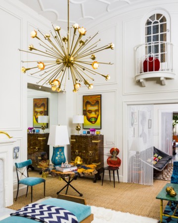 A designer gold chandelier in a living room with a Jonathan Adler touch.