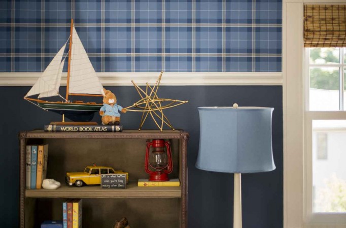 A cozy room with a bookcase and a sailboat decorated in blue and white.