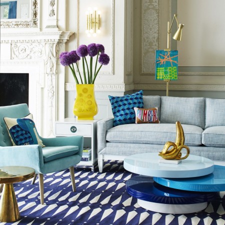 A living room with a blue couch and a blue rug, designed by Jonathan Adler.