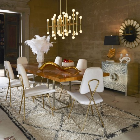 A dining room with a white table and chairs designed by Jonathan Adler, the King of Happy Chic.