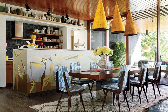 A dining room with a wooden table and chairs designed by Jonathan Adler, the King of Happy Chic.