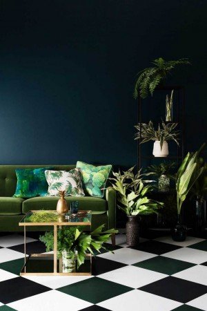 Creating a tropical oasis at home with a green couch and black and white checkered floor.