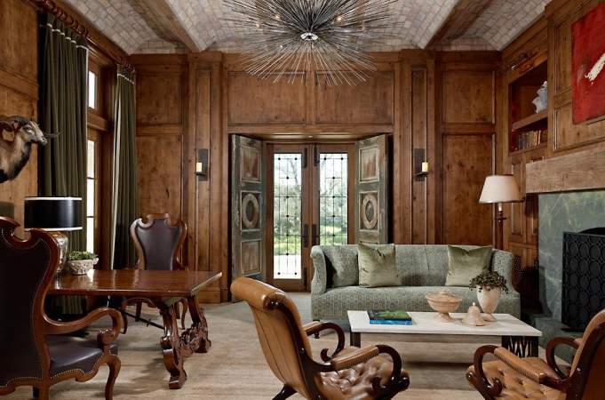 A living room with wood paneled walls and a fireplace designed with a touch of haute couture interior design.